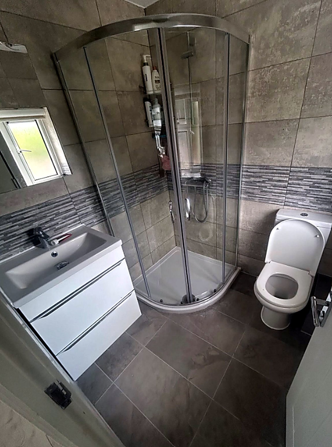 Modern grey-tiled shower room with glass enclosure, vanity and WC, bathroom fitting in Cambridge