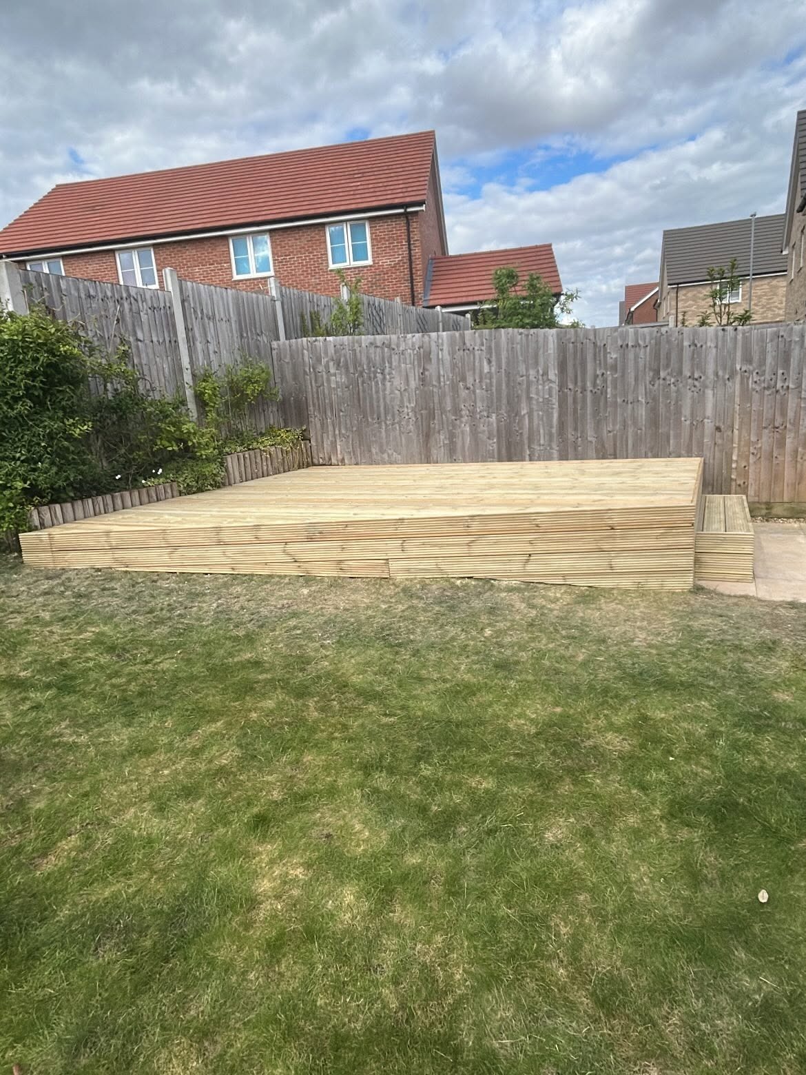 Wide view of a finished raised timber deck against a brick house in Cambridgeshire